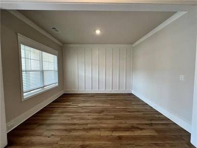 Empty room featuring ornamental molding, dark wood-style flooring, baseboards, and recessed lighting