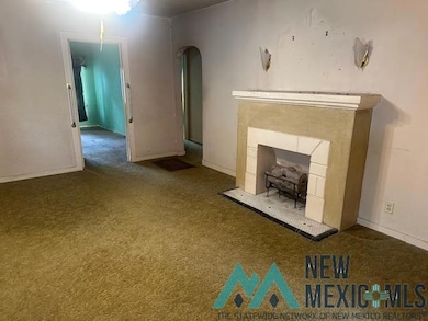 Unfurnished living room featuring carpet, arched walkways, and a tiled fireplace