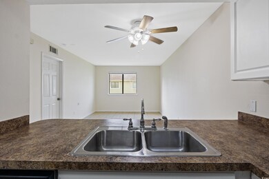 Kitchen with white cabinets, sink, and ceiling fan