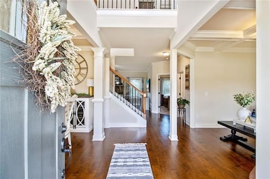 Foyer featuring dark wood-type flooring, ornamental molding, beamed ceiling, coffered ceiling, and stairway