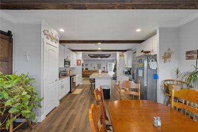 Dining area with dark wood-style floors, recessed