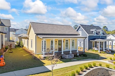 View of front facade with covered porch, a front yard, and roof with shingles