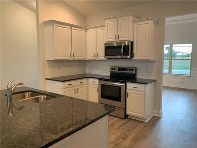 Kitchen with a sink, white cabinets, light wood-st