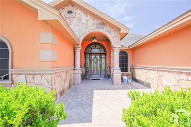 Doorway to property featuring stone siding, stucco siding, and a shingled roof