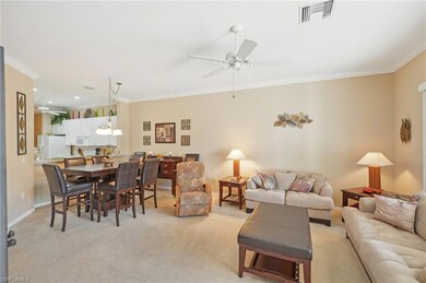 Living area featuring light colored carpet, crown molding, visible vents, baseboards, and ceiling fan