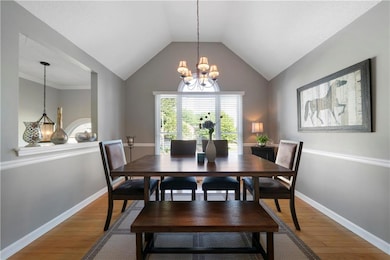 Dining room featuring hardwood / wood-style flooring, a chandelier, and vaulted ceiling