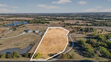 Aerial view of property's location with a large body of water, property parcel outlined, and rural landscape