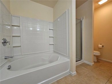 Bathroom featuring a garden tub, a shower stall, and light tile patterned floors