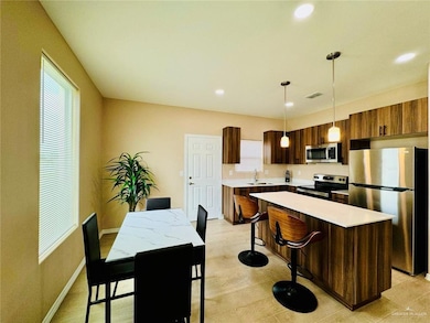 Kitchen featuring appliances with stainless steel finishes, modern cabinets, a center island, decorative light fixtures, and a kitchen bar