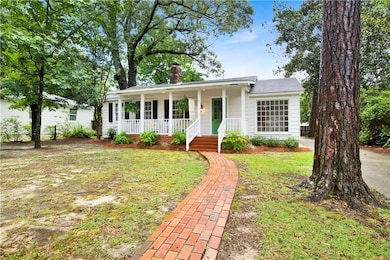 Ranch-style home featuring covered porch, a chimney, and a front yard