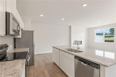 Kitchen with a sink, white cabinets, appliances wi