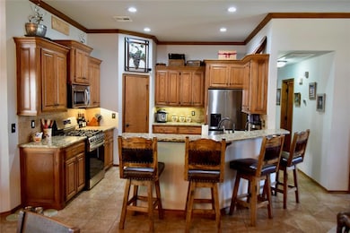Kitchen with stainless steel appliances, ornamental molding, brown cabinets, backsplash, and recessed lighting