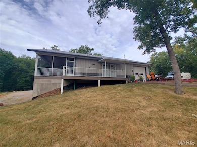 Rear view of house featuring a sunroom, a wooden deck, an attached garage, and a yard