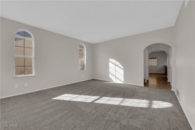 Spare room featuring arched walkways, carpet, and healthy amount of natural light