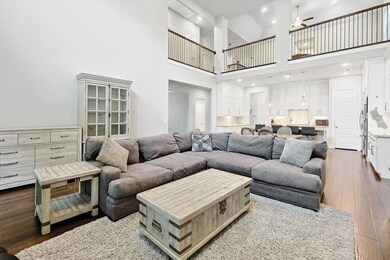 Living room featuring wood-type flooring, ceiling fan, and a high ceiling