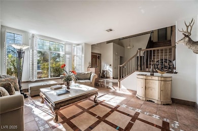Tiled living room featuring inlaid floor details, stairway, and a chandelier