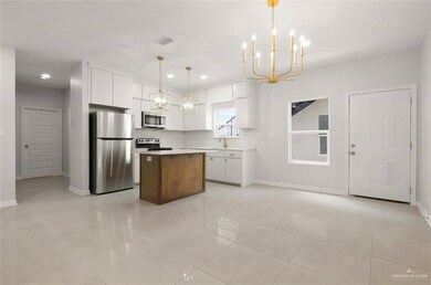 Kitchen featuring stainless steel appliances, a center island, light tile patterned flooring, pendant lighting, and white cabinets