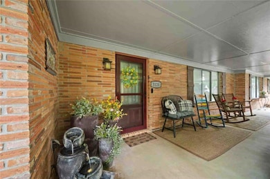 View of exterior entry featuring brick siding and a porch