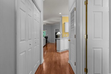 Corridor with ornamental molding, wood finished floors, baseboards, and recessed lighting