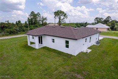 Rear view of property with a yard, stucco siding, a patio, and roof with shingles