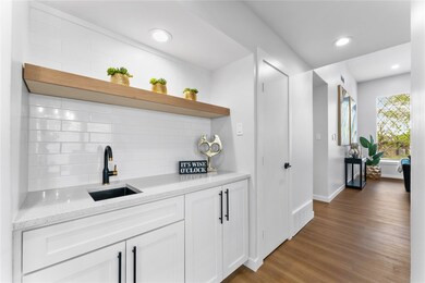 Wet Bar with backsplash, a sink, wood finished flo