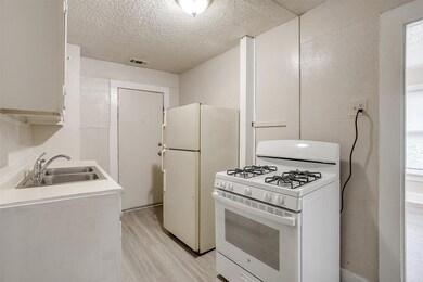 Kitchen with white gas range, a textured ceiling, light wood-style flooring, and light countertops