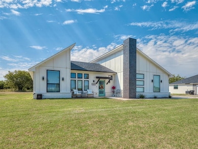 View of front of house featuring board and batten siding, a front yard, and roof with shingles