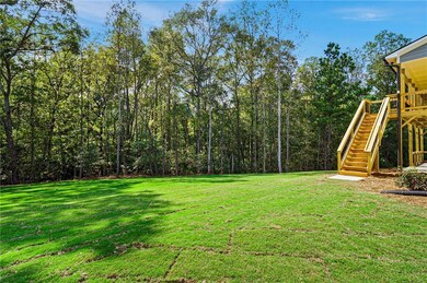 View of grassy yard featuring stairway and a deck