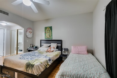 Bedroom featuring arched walkways, wood finished f