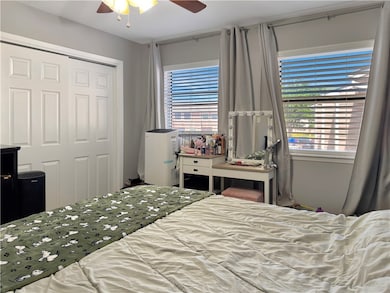 Bedroom with ceiling fan, a closet, and multiple w