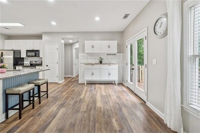 Kitchen with appliances with stainless steel finishes, dark wood-style flooring, white cabinetry, baseboards, and recessed lighting