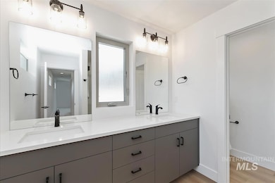 Full bathroom with double vanity and light wood-type flooring