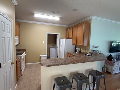 Kitchen with ornamental molding, a textured ceiling, a peninsula, white appliances, and dark countertops