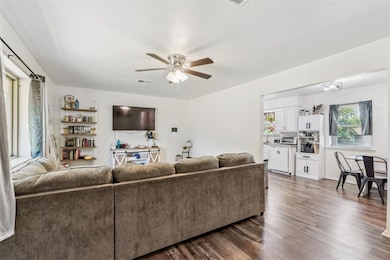 Living area featuring a ceiling fan and dark wood-style flooring