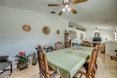 Dining room with a ceiling fan, arched walkways, light tile patterned floors, and lofted ceiling