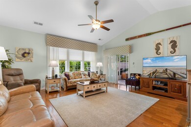 Living room with ceiling fan, wood finished floors, and lofted ceiling