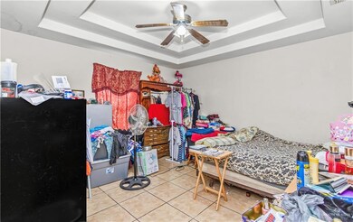 Tiled bedroom with ceiling fan and a tray ceiling