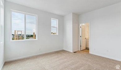 Unfurnished bedroom with light carpet and ensuite bathroom
