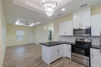 Kitchen with a raised ceiling, stainless steel appliances, a peninsula, dark countertops, and open floor plan