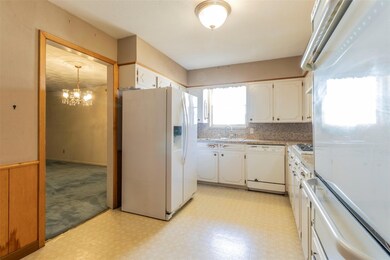 Kitchen featuring white appliances, a chandelier, 