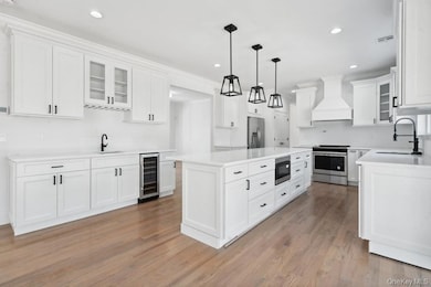 Kitchen with premium range hood, stainless steel appliances, a center island, a sink, and beverage cooler