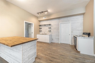 Kitchen with wood finished floors, white cabinets, white range with electric stovetop, butcher block counters, and open shelves