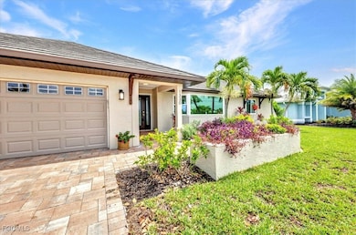 View of front facade featuring stucco siding, a front yard, an attached garage, and driveway