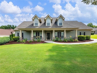 View of front of house with a shingled roof, a front lawn, stone siding, and a porch