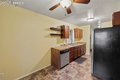 Kitchen featuring freestanding refrigerator, dishwasher, open shelves, light countertops, and a ceiling fan