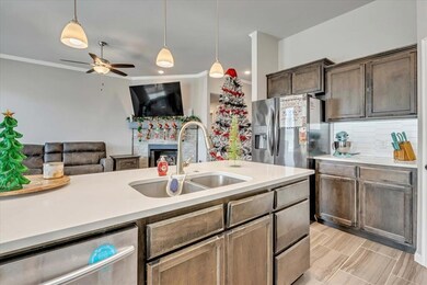 Kitchen with open floor plan, stainless steel appliances, hanging light fixtures, ornamental molding, and tasteful backsplash