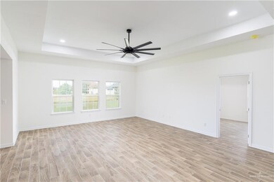 Spare room featuring light wood finished floors, ceiling fan, recessed lighting, and a raised ceiling