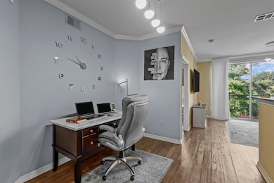 Home office with wood finished floors, crown moldi