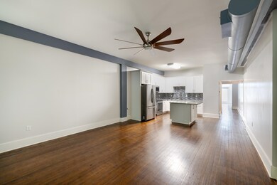Kitchen featuring freestanding refrigerator, a ceiling fan, decorative backsplash, light countertops, and a center island