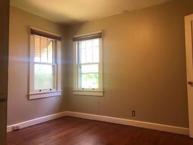 Empty room featuring baseboards and dark wood finished floors